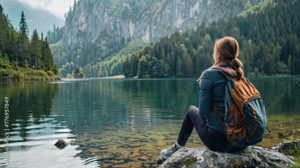 Woman sitting on a stone and looking to a beautiful lake Woman sitting on a stone and looking to a beautiful lake