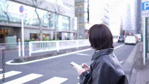 Slow-motion video of a Japanese woman in her 20s walking around Gotanda Station, Shinagawa-ku, Tokyo while operating her smartphone in winter 冬の東京都品川区五反田の駅周辺をスマートフォンを操作しながら歩く20代の日本人女性のスローモーション映像 photo