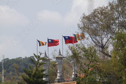 Two Taiwanese (Republic of China) flags and two buddhist flags waving between green trees at Fo guang shan monastery in early spring. photo