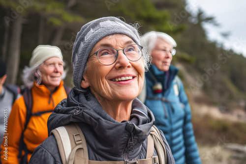 Smiling old gray-haired woman hiking in nature in the company of other women