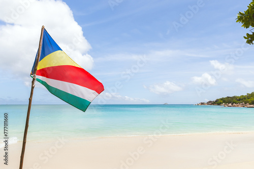 The flag of Seychelles is on the beach on a sunny summer day
