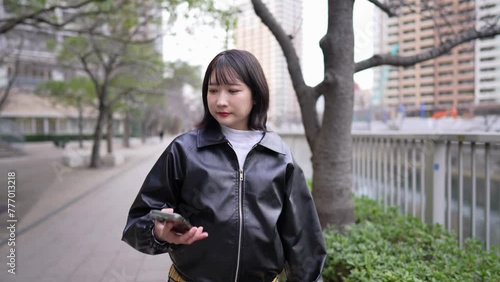 Slow-motion video of a Japanese woman in her 20s walking around Gotanda Station, Shinagawa-ku, Tokyo while operating her smartphone in winter 冬の東京都品川区五反田の駅周辺をスマートフォンを操作しながら歩く20代の日本人女性のスローモーション映像 photo