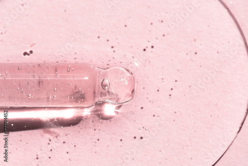 Drops of liquid hyaluronic acid on a pink background with a pipette, collagen for the skin.