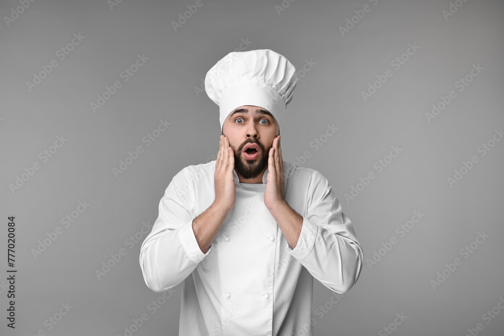 Surprised young chef in uniform on grey background Surprised young chef in uniform on grey background