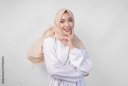 Elegant young Asian Muslim woman wearing white dress with hijab waving in the wind, modelling pose on white background