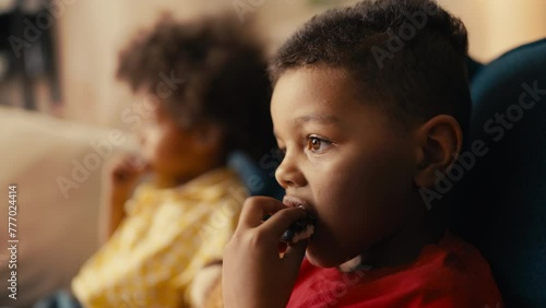 Little African American boys eating chocolate cookies, children enjoying sweets photo