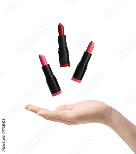 Woman making lipsticks levitate on white background, closeup. Decorative cosmetics