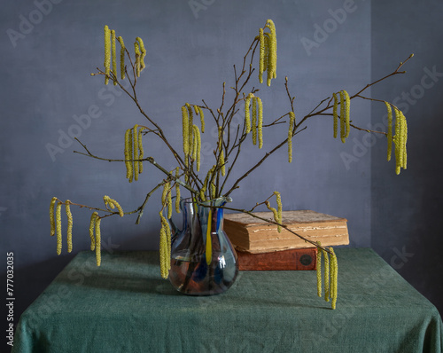 Still life with a bouquet of hazel branches with earrings and books.