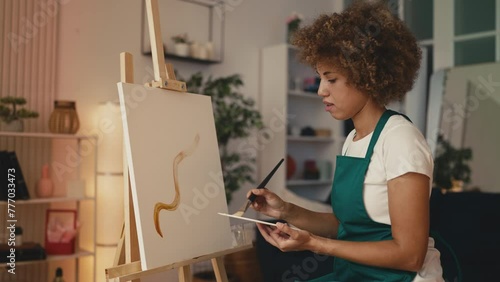 African American woman artist making brushstrokes while painting on a canvas photo