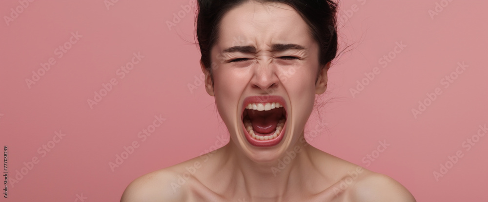 Studio portrait of woman screaming and yelling with hormonal PMS rage, pink background
