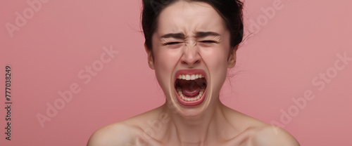 Studio portrait of woman screaming and yelling with hormonal PMS rage, pink background
 photo