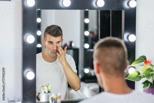 Drag queen artist applying concealer while doing his makeup in the dressing room. photo