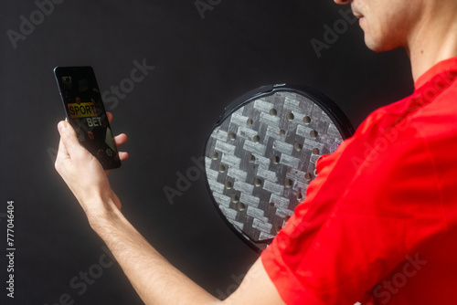 man holding paddel racket and smartphone with bet black background