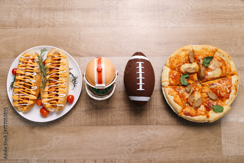 Superbowl theme with rugby ball, helmet, hotdogs and tasty pizza on wooden background photo
