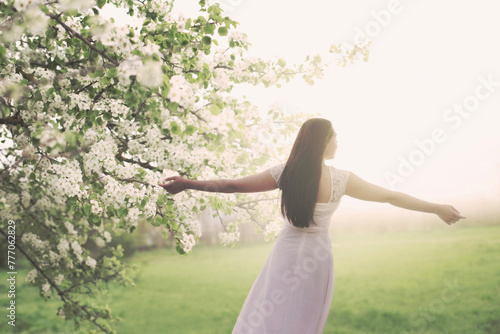 young woman dressed in white taking a breath in the middle of spring nature