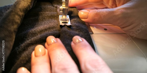 process of sewing in a sewing machine sew woman's hands manicure black textile denim jeans manufacturing close up seamstress in workshop fabric clothes making design hobby handmade working needlework