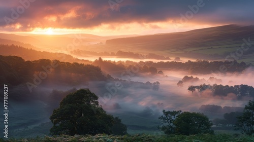 The sun is setting over a foggy landscape, with trees and hills in the background. The sky is a mix of orange and pink hues, creating a serene and peaceful atmosphere