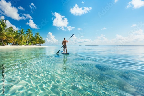 Aerial photo of unidentified man practicing stand up paddle board or SUP in tropical exotic turquoise calm sea sandy beach photo