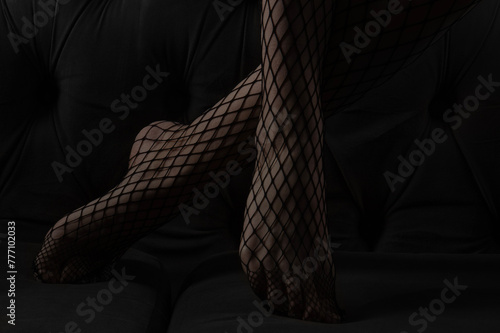 Close-up female feet. Legs in black stockings on black background