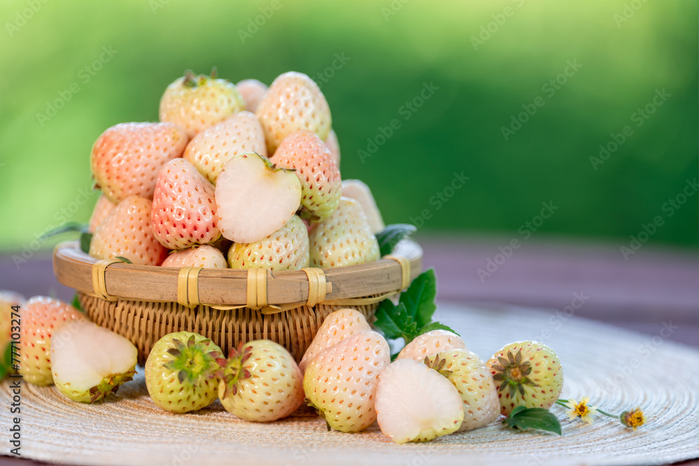 White Strawberries on wooden table in garden, Pink snow strawberry in wooden plate on blurred greenery background. White Strawberries on wooden table in garden, Pink snow strawberry in wooden plate on blurred greenery background.