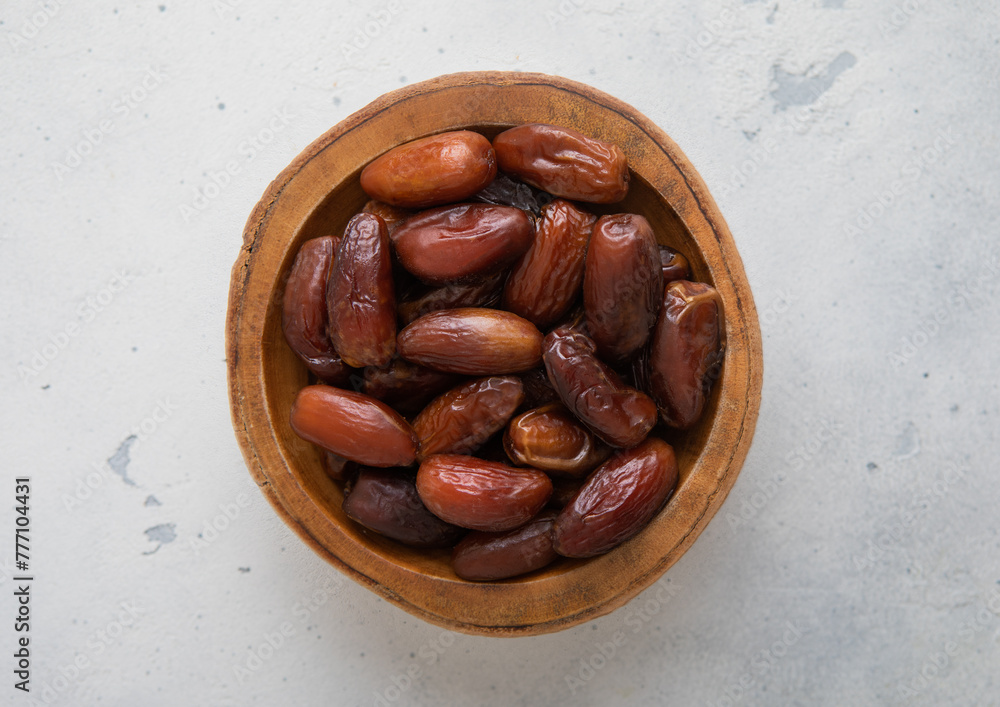 Fototapeta premium Wooden bowl of dried sweet brown dates on light background.Top view.