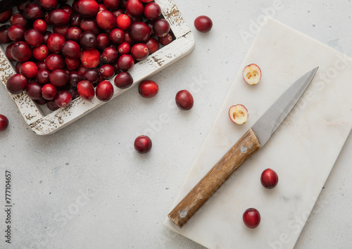 Wooden box with red ripe cranberries and kitchen knife on light background.Top view.