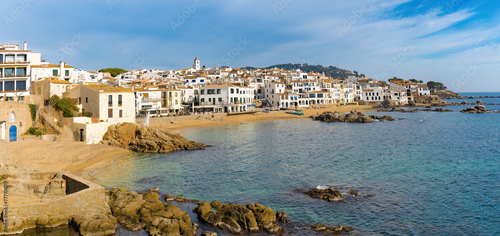 Panorámica de Calella de Palafrugell, donde las casas blancas con detalles azules se mezclan con el paisaje costero rocoso y las aguas del Mediterráneo.