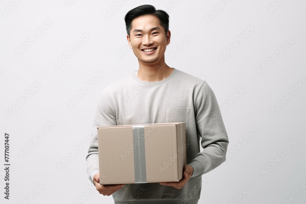 Happy Young Man Carrying a Cardboard Box. Asian man holding package parcel box. Delivery courier and shipping service concept on white background. Generative AI. Happy Young Man Carrying a Cardboard Box. Asian man holding package parcel box. Delivery courier and shipping service concept on white background. Generative AI.