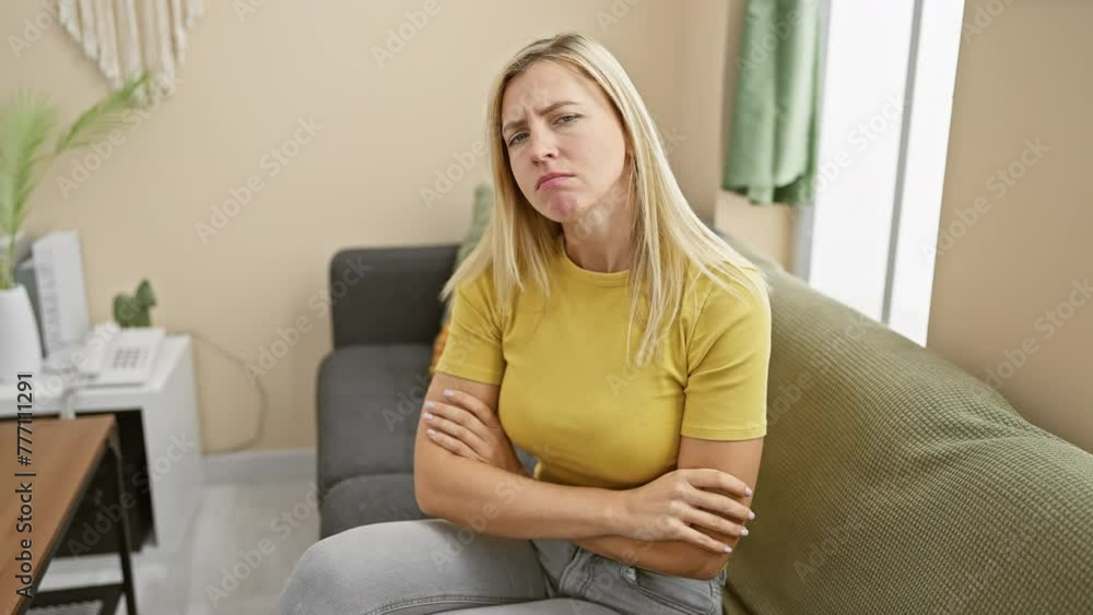 Skeptical young blonde woman, crossed arms and nervous frown at home. emoting displeasure, portrait of negative expression—beauty embroiled in incredulity indoors Skeptical young blonde woman, crossed arms and nervous frown at home. emoting displeasure, portrait of negative expression—beauty embroiled in incredulity indoors