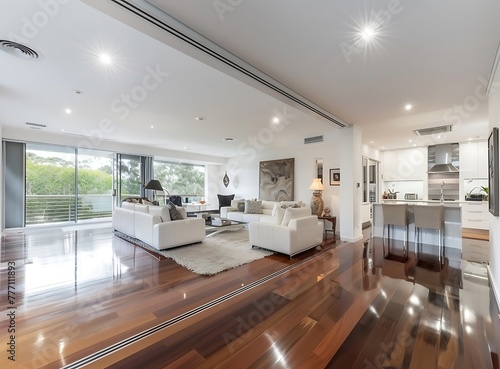 A wide-angle photo of an open-plan modern Australian home with white walls and a dark timber floor