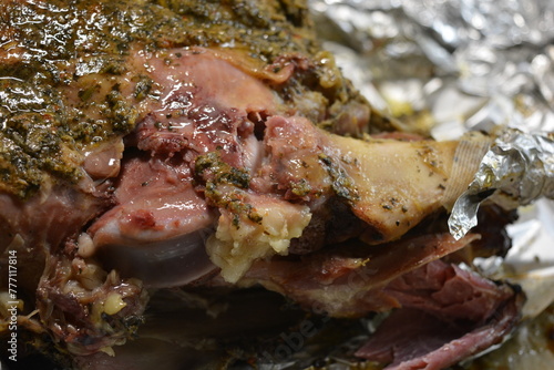 Eating, cooking delicious meat, sheep leg on the bone marinated and baked in the oven. A large piece of lamb arranged on brown parchment paper.