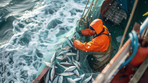 A fisherman on a trawler with a net full of fish. Commercial fishing in the sea. Work on a fishing boat photo