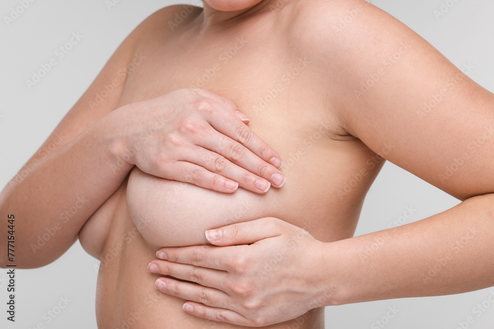 Mammology. Naked woman doing breast self-examination on light grey background, closeup Mammology. Naked woman doing breast self-examination on light grey background, closeup