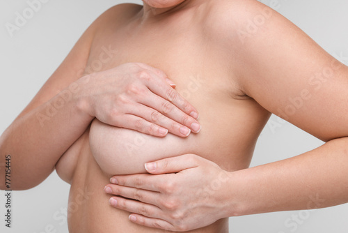 Mammology. Naked woman doing breast self-examination on light grey background, closeup