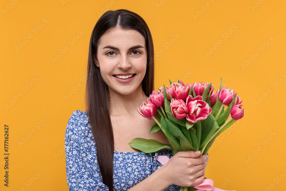 Happy young woman with beautiful bouquet on orange background Happy young woman with beautiful bouquet on orange background