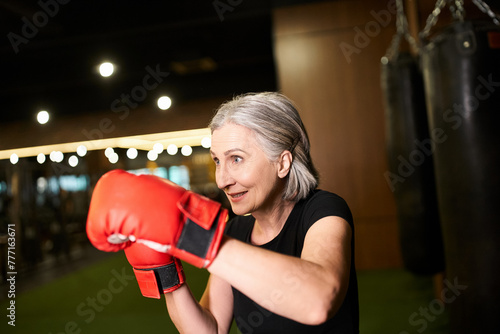 athletic mature attractive woman with gray hair posing with boxing gloves while training in gym © LIGHTFIELD STUDIOS