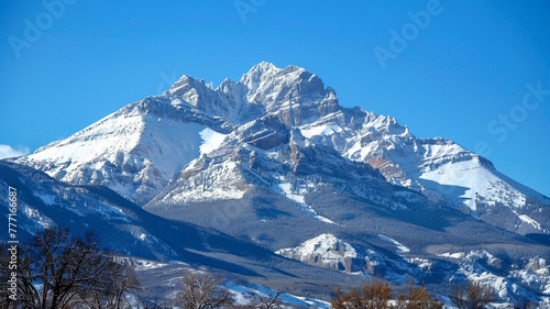 Magnificent mountain range covered in a blanket of snow, against a clear blue sky.