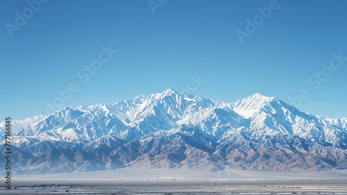 Magnificent mountain range covered in a blanket of snow, against a clear blue sky.
