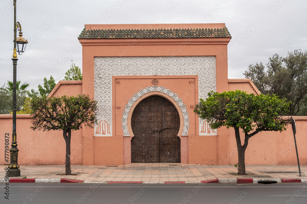 Wooden door in Marrakesh, Morocco. Moroccan closed archway gate in stone terracotta wall with islamic ornaments