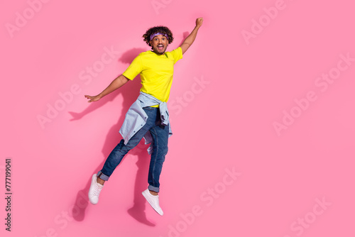 Photo of funky excited positive man wear trendy clothes fly air raised hand empty space isolated on pink color background