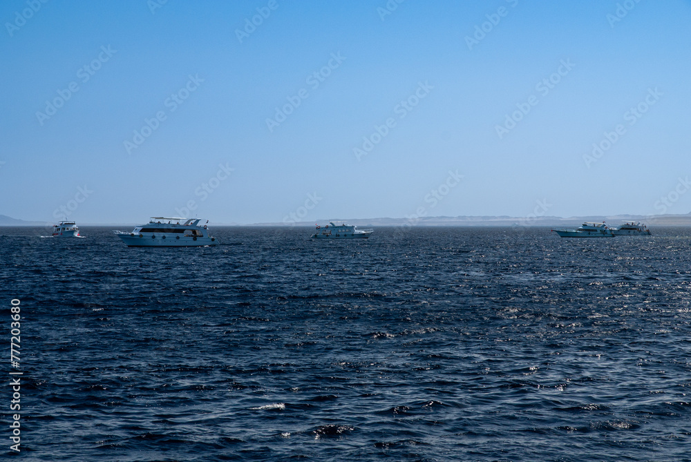 White yachts with tourists are moving on open sea. Yacht hulls cut through turquoise waters of Red Sea. Horizon line separates sea and sky. Sharm el-Sheikh, Egypt, April 20, 2008 White yachts with tourists are moving on open sea. Yacht hulls cut through turquoise waters of Red Sea. Horizon line separates sea and sky. Sharm el-Sheikh, Egypt, April 20, 2008