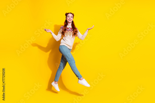 Photo portrait of attractive young woman jumping walk raise hands dressed stylish knitted warm outfit isolated on yellow color background
