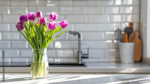 Purple tulips in a glass jar standing on the modern kitchen with white tile #777210665