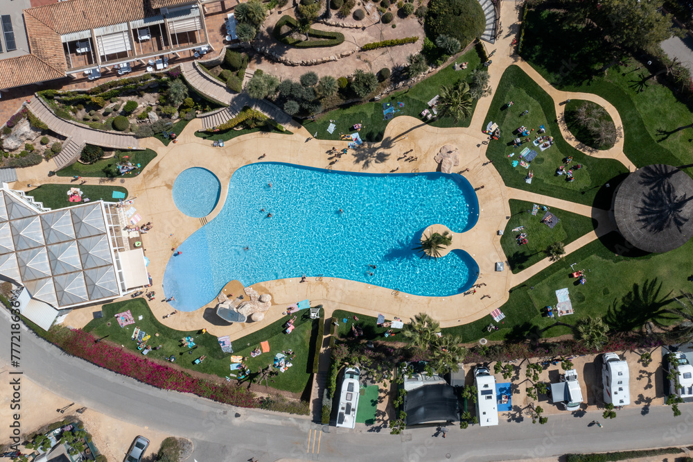 Aerial photo of the town of Benidorm in Spain showing a drone view of a camp site with many motorhomes and caravans on the camping site an a outdoor swimming pool with families on vacation having fun