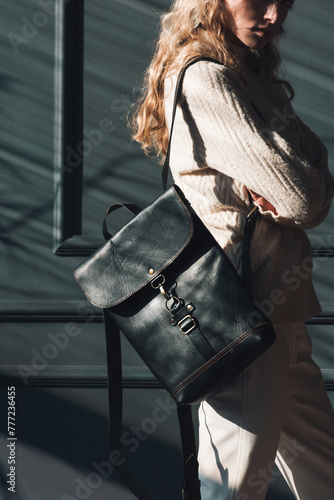 Studio portrait of beautiful woman with a curly blond hair holding brown bag, posing on gray background.