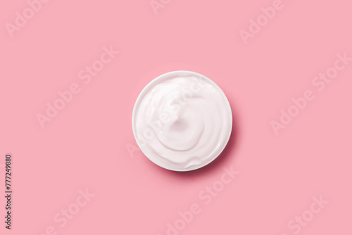 Cream jar of white on a pink background.