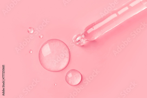 The gel dripping from the dropper is transparent in the form of round droplets  on a pink background. photo
