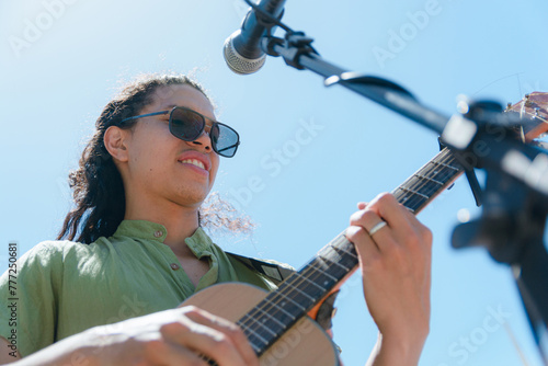 Latin man guitarist musician with good attitude making rock music with his acoustic guitar outdoors. photo