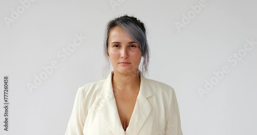 Woman look straight to camera, try to look strong, portrait shot against white background. Girl with dyed hair fixedly stare to us, but may be hide small smile on her face photo