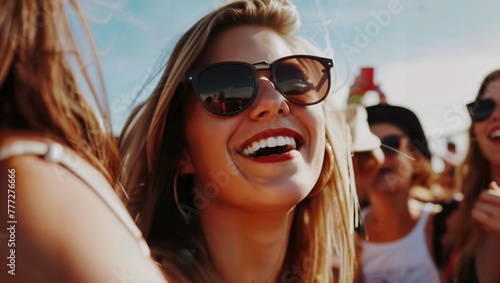 A young woman with her friends, all wearing sunglasses, laughing at the camera during an open-air festival.
